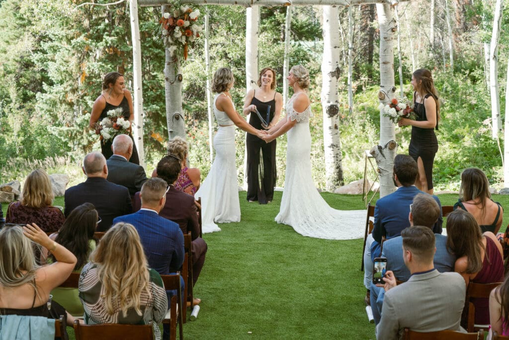 A queer couple getting married in a micro wedding ceremony at Sky Valley Chateau in Steamboat Springs surrounded by their favorite people