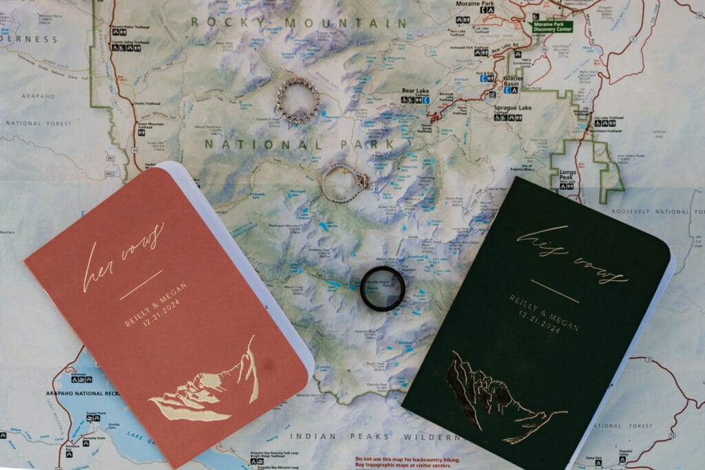 Rocky Mountain National Park map used as the background of a detail photo featuring a newlywed couples' wedding rings and vow books