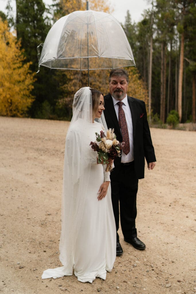 A bride and her father preparing to walk down the aisle of aspens to her elopement ceremony
